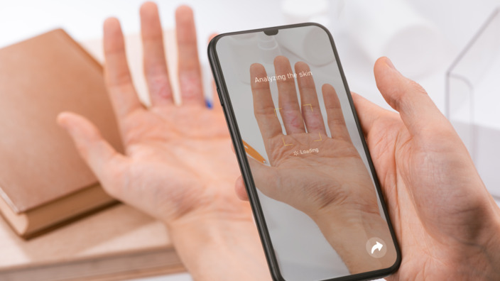 Person fotografiert seine Hand mit dem Handy