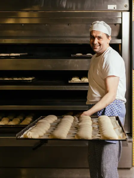 Bäcker in Goldbrötchen Bäckerei holt Brötchen aus dem Ofen