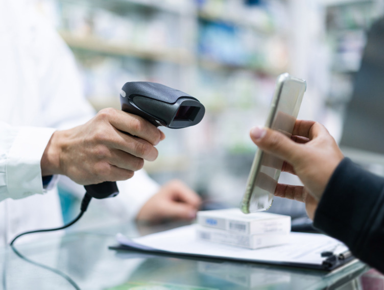 Apotheker richtet Scanner auf Handy eines Kunden