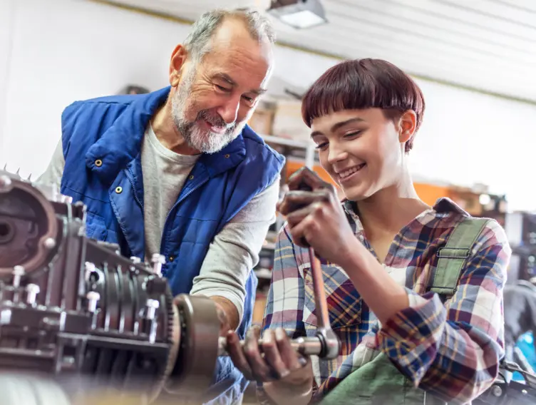 Älterer Mitarbeiter lernt eine Auszubildende an der Maschine an