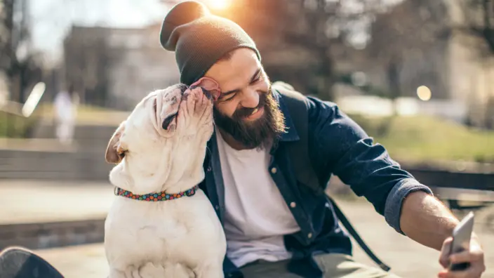 Mann lässt sich von seinem Hund sein Gesicht abschlecken.