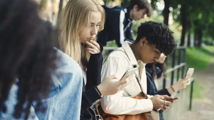 Jugendlich habe ihr Handy in der Hand und schauen auf den Bildschirm