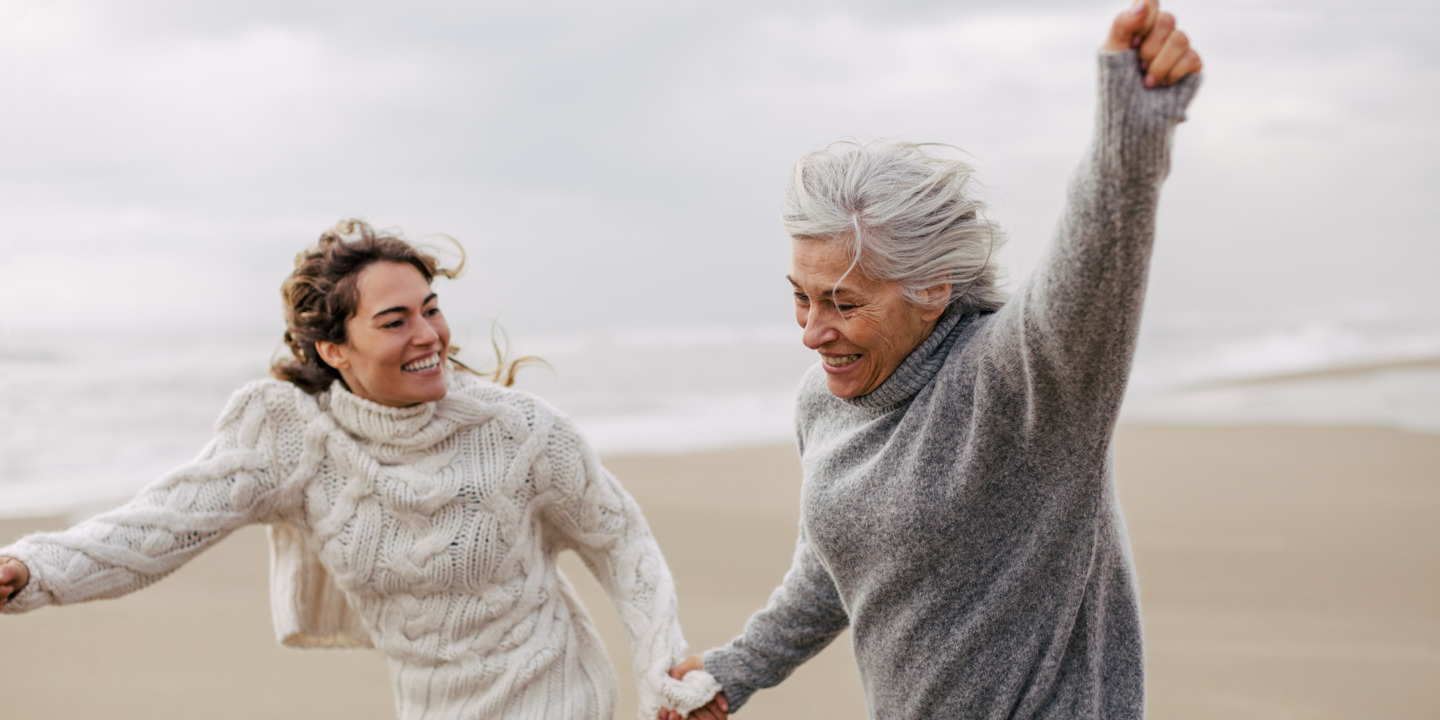Mutter und Tochter laufen am Strand entlang und halten sich an der Hand.