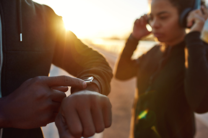 Junge Menschen nutzen Fitness-Apps im Sonnenuntergang