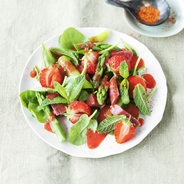 Spargelsalat mit Erdbeeren, Babayspinat, Rhabarber und Minze auf einem Teller serviert