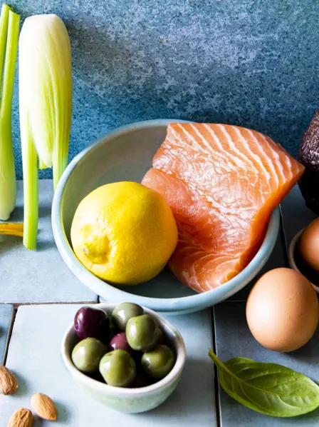 Erlaubte Lebensmittel einer Keto Diät wie Lachs, Avocado, Eier, Oliven, Sellerie und Nüsse