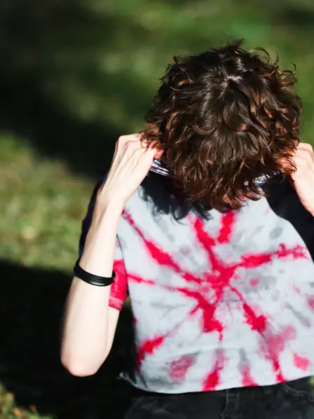 Person mit Burn-out vergräbt Gesicht in T-Shirt