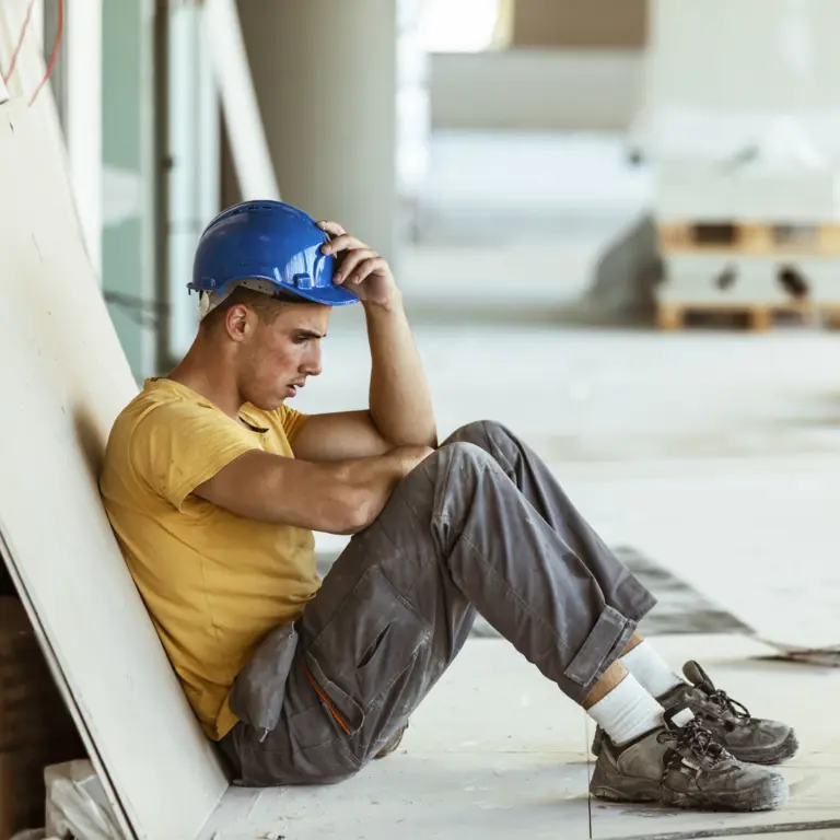 Handwerker mit Burn-out sitzt niedergeschlagen am Boden