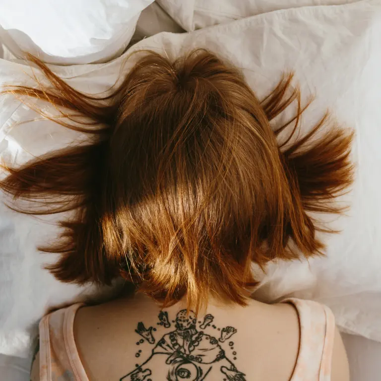 Frau versteckt ihr Gesicht im Kopfkissen – Symbolbild für Müdigkeit