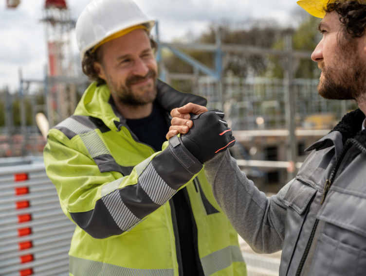 Zwei Bauarbeiter machen einen Handschlag. 