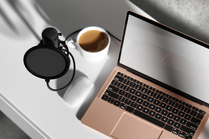 Ein Tisch mit Mikrofon, Laptop und Kaffeetasse