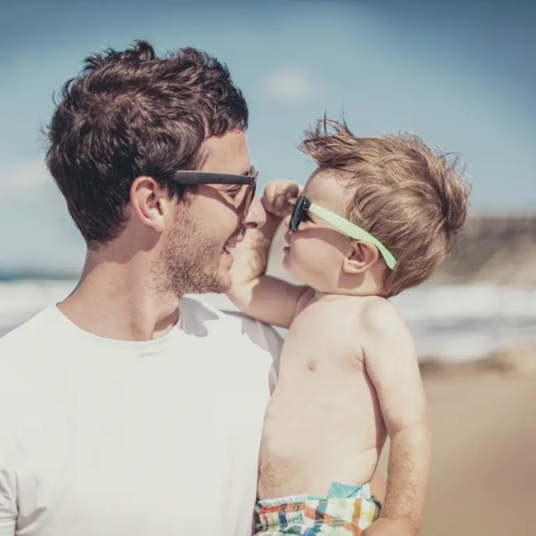 Vater und Sohn betrachten sich durch Ihre Sonnenbrillen am Strand
