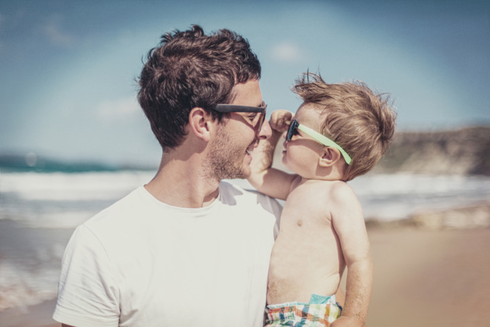 Vater und Sohn betrachten sich durch Ihre Sonnenbrillen am Strand