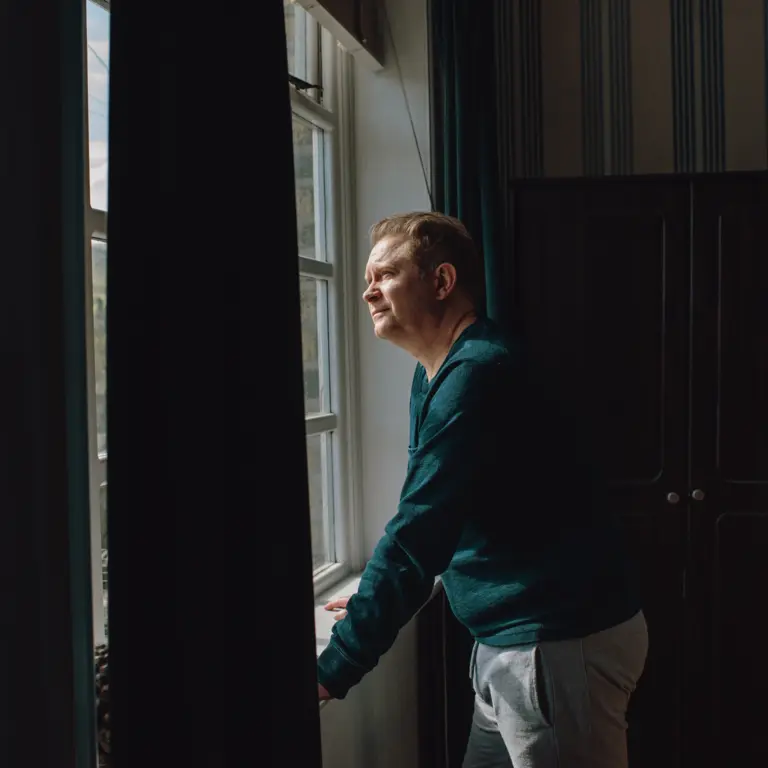 Mann schaut nachdenklich aus dem Fenster