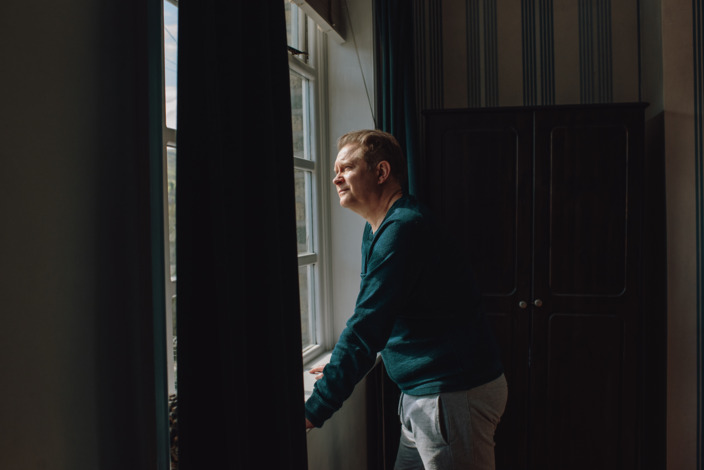 Mann schaut nachdenklich aus dem Fenster