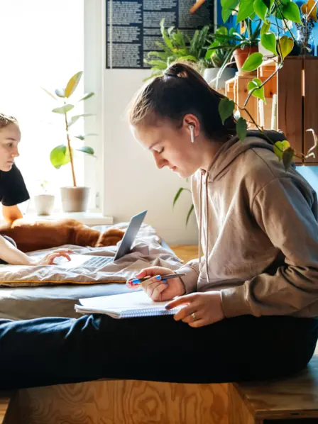 Zwei Geschwister sitzen gemeinsam Zuhause im Zimmer