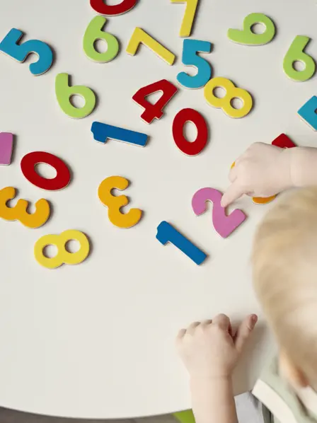 Kleinkind spielt mit Zahlen auf einem Tisch