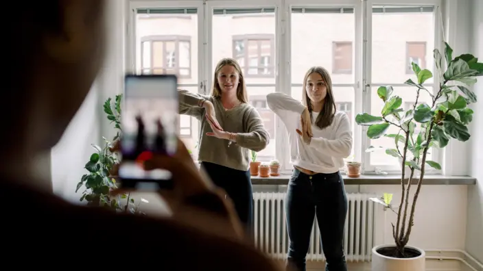 Zwei junge Frauen Tanzen vor der Handykamera.