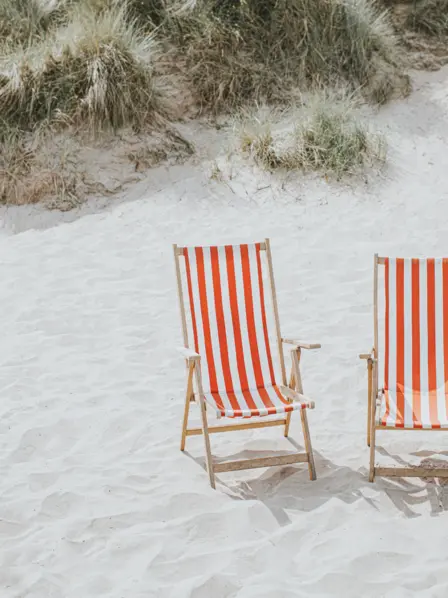 Zwei leere Liegestühle am Strand.