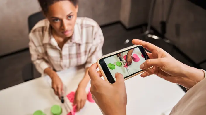 Frau filmt mit Smartphone Bloggerin, die kinetischen Sand schneidet