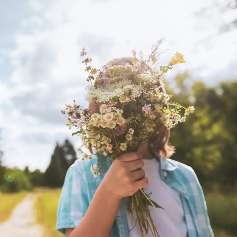 Kind hält einen Blumenstrauß vor sein Gesicht