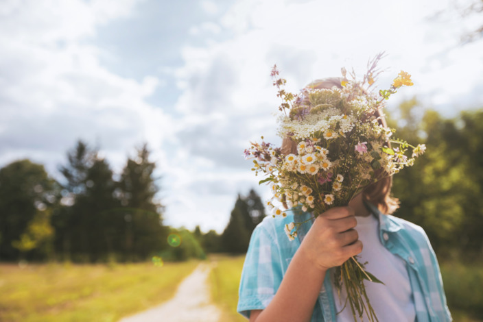 Kind hält einen Blumenstrauß vor sein Gesicht