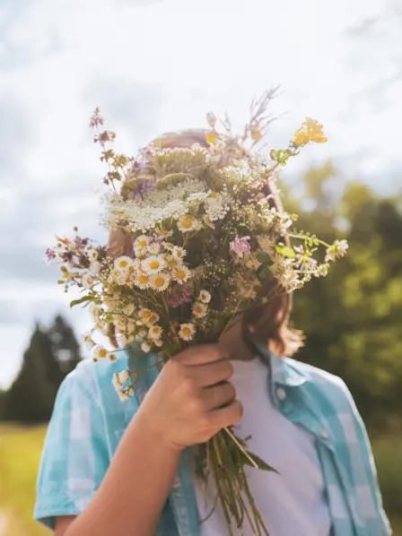 Kind hält einen Blumenstrauß vor sein Gesicht