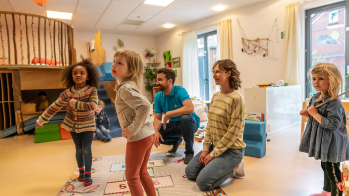 Kinder spielen im Kindergarten mit Erzieherin und Erzieher