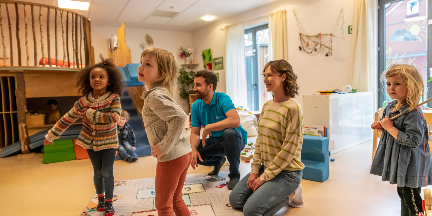 Kinder spielen im Kindergarten mit Erzieherin und Erzieher