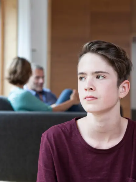 Jugendlicher sitzt mit dem Rücken zu seinen Eltern