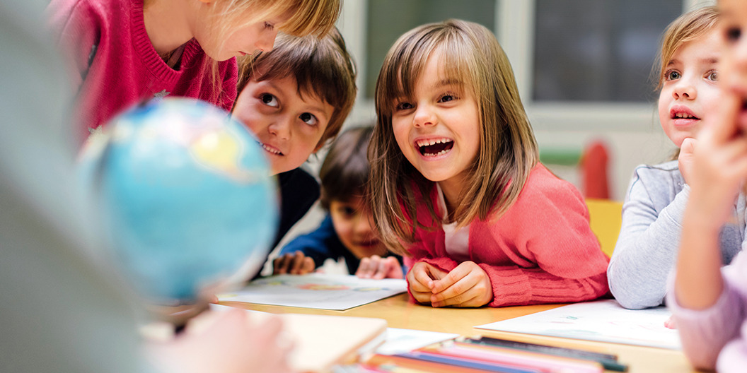 Kinder sitzen im Klassenraum an einem Tisch und lernen