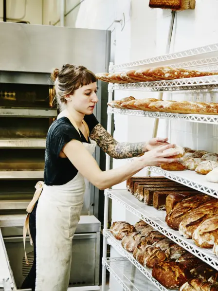 Junge Bäckerin sortiert Brot in der Backstube