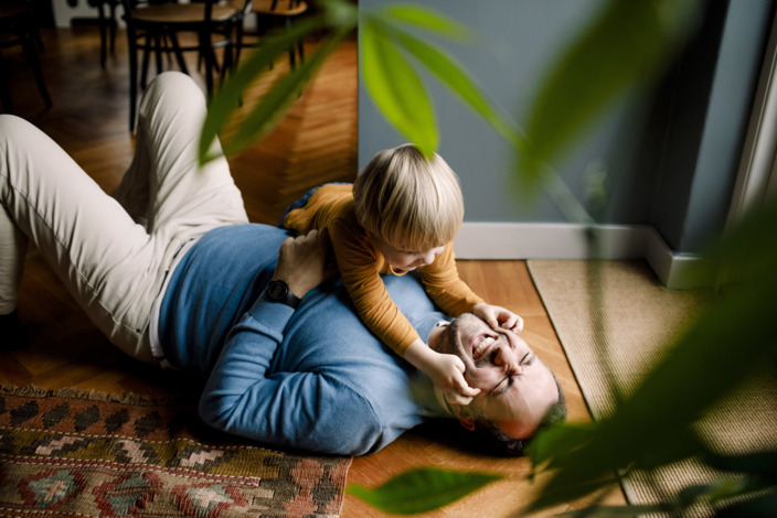 Vater und Sohn albern auf dem Boden herum