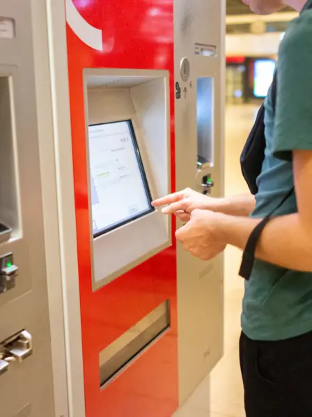 Teenager kauft eine Fahrkarte am Fahrkartenautomat
