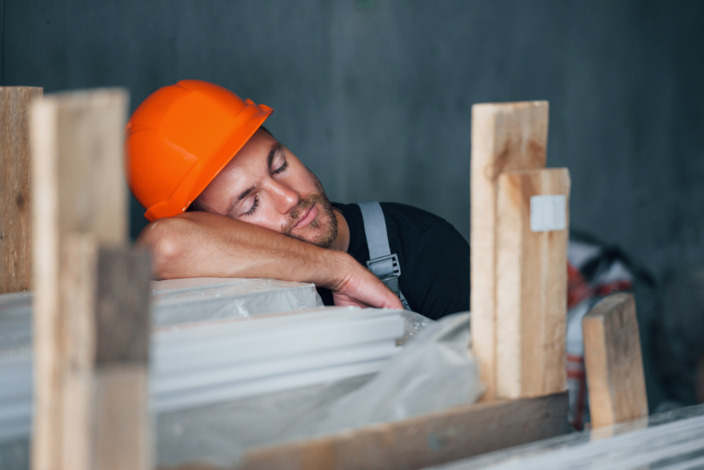 Handwerker mit Helm macht Mittagsschlaf