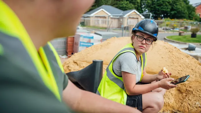 Junge Handwerkerin unterhält sich mit ihrem Kollegen.