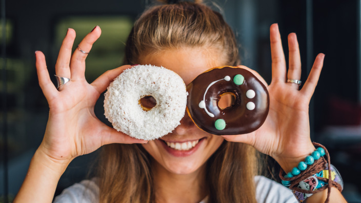 Frau hält sich Donuts vor die Augen