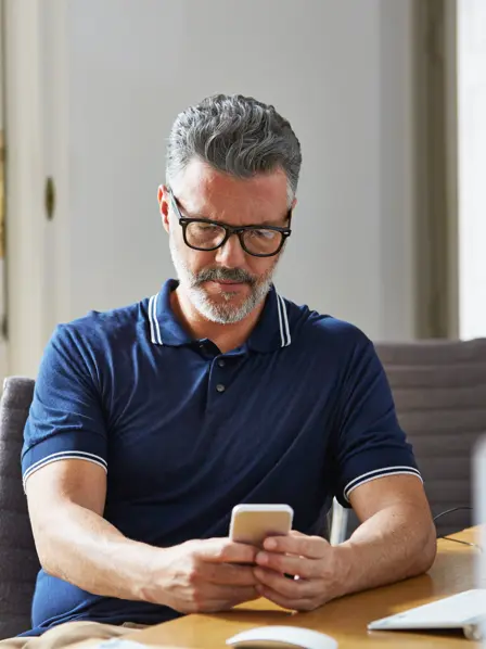 Mann sitzt mit Handy am Tisch