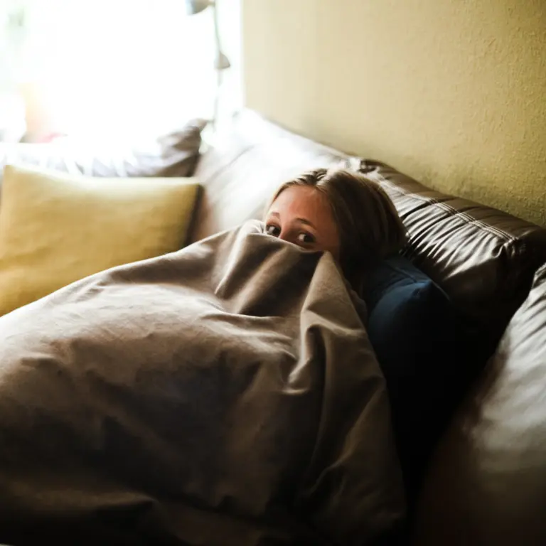 Junge Frau versteckt sich unter einer Decke