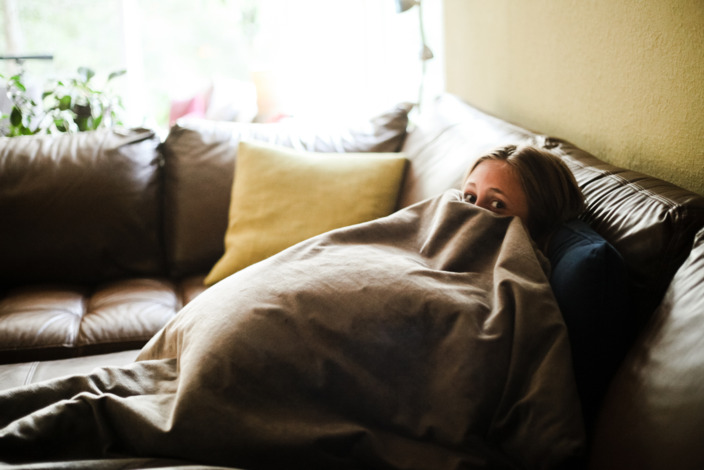 Junge Frau versteckt sich unter einer Decke