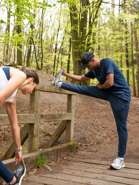 Mann und Frau strechen sich vorm Joggen.