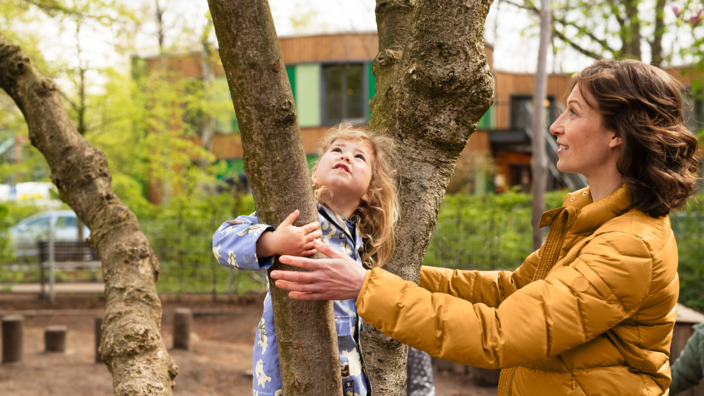 Kindergartenkind und Erzieherin auf einem Spielplatz in der Natur