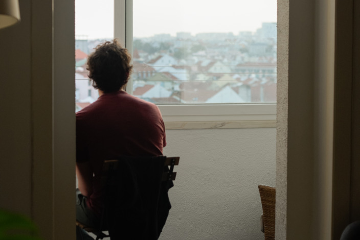 Mann sitzt traurig vor dem Fenster