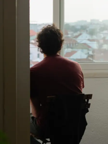 Mann sitzt traurig vor dem Fenster