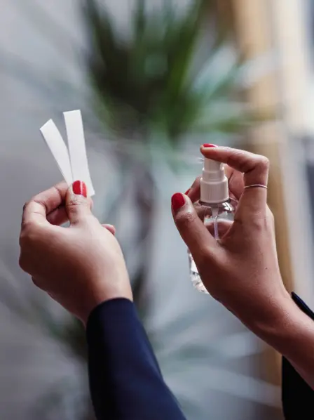 Eine Frau besprüht Papierstreifen mit Parfum.