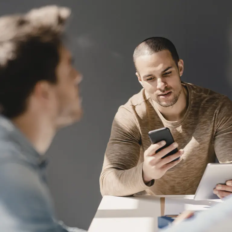 Arbeitskollegen im Büro benutzen ein Smartphone