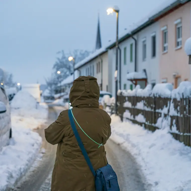 Eine Person steht auf einer schneebedeckten Straße.
