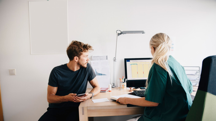 Junger Mann sitzt bei der Ärztin