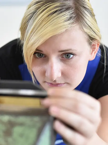 Junge Frau beugt sich über eine Werkbank und misst etwas aus.