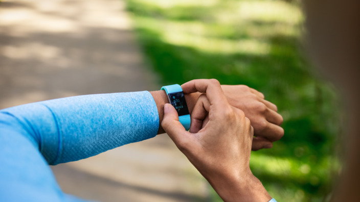 Joggerin bedient ihren Fitness-Tracker um ihre Vitalwerte im Blick zu halten.